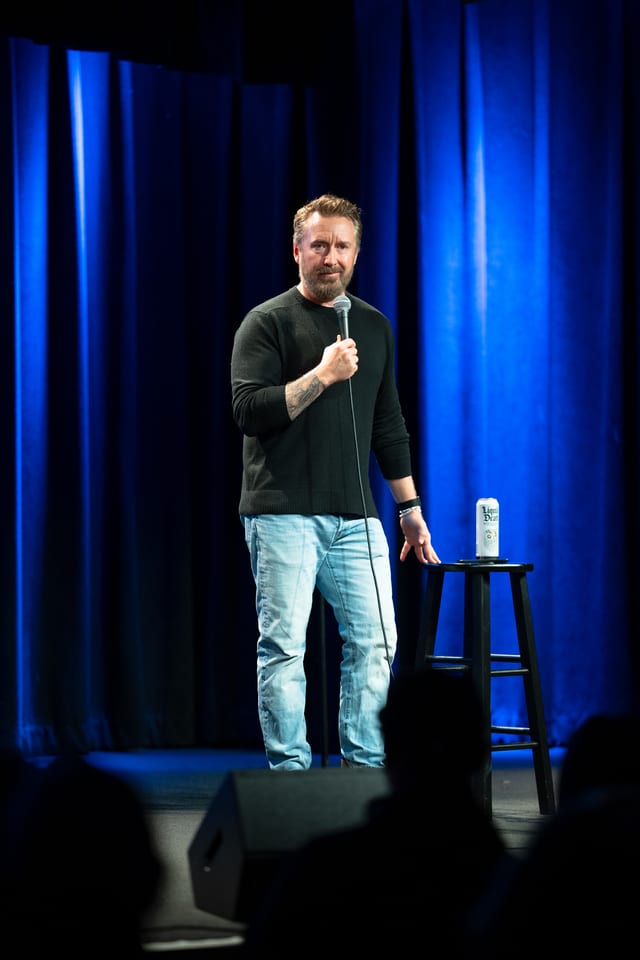 Chad Daniels on the blue-curtained stage at Cobb's Comedy Club.